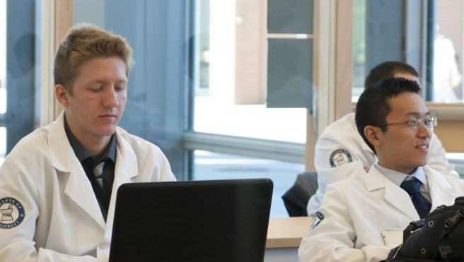 two lab students use their laptops in a classroom