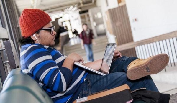 a student uses their laptop in a hallway