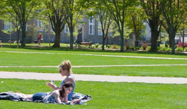 two students sit in the quad at URI's Kingston campus on a sunny day