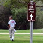 dog park sign with a man walking in the background