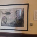A framed drawing showing a soldier with a helicopter in the distance, at the Veteran Stories exhibit, URI’s Feinstein campus. PHOTO CREDIT: Aidan Cahill