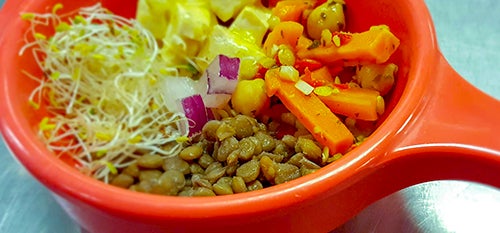 close up of grain bowl featuring sprouts, veggies, and lentils