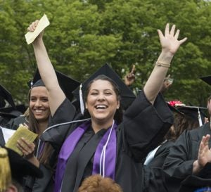 graduate with hands raised at commencement