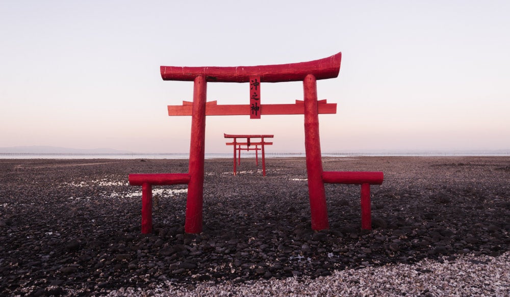 Red painted gateways on a beach in Japan