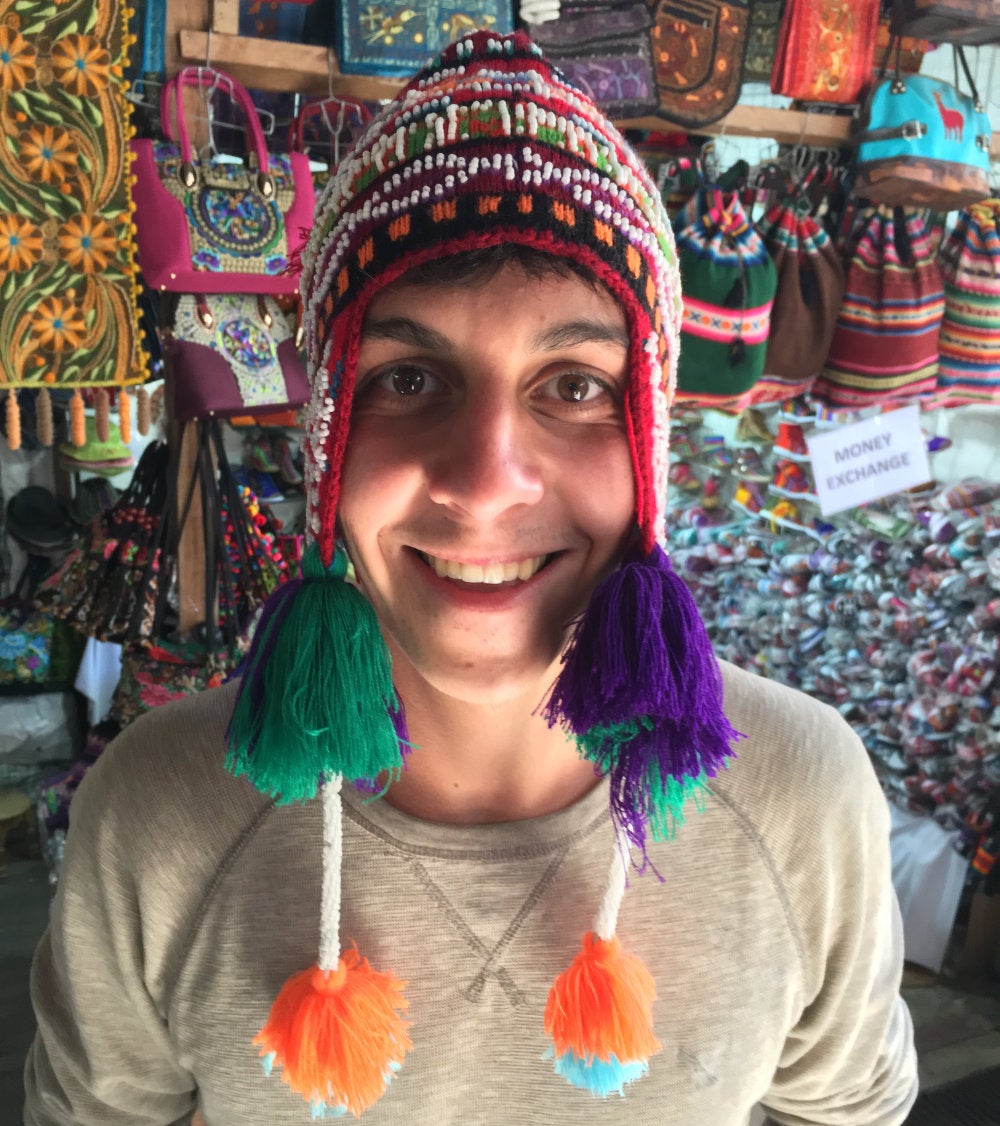 A student trying on a hat in a Peruvian market
