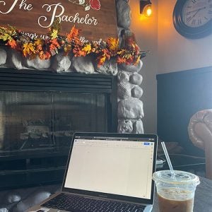 Fall decor near a fire place laption and iced latte in foreground