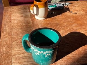Two coffee mugs on a table lit up by the golden sun