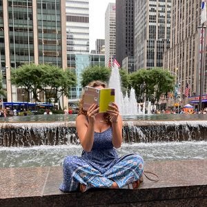 Tara sitting on a fountain reading a book in ny city