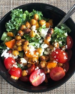 Pictures is a salad topped with kale, chickpeas, tomatoes, and peppers