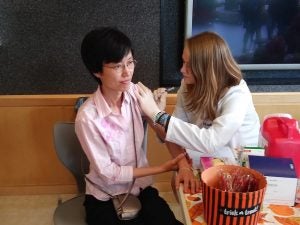 Fourth-year Pharmacy student Erin Connolly injects Xiaofeng Lin with the flu vaccine during a clinic in Avedisian Hall 