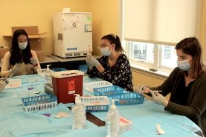 Clinical Assistant Professor Britny Brown works with students Melissa Gianetti and Yan Cen preparing vaccines at the Westerly Senior Center.