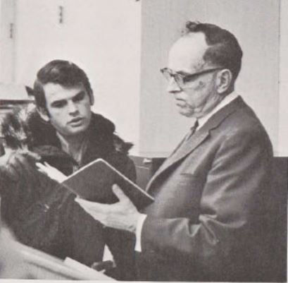 old picture of business professor reading book to student