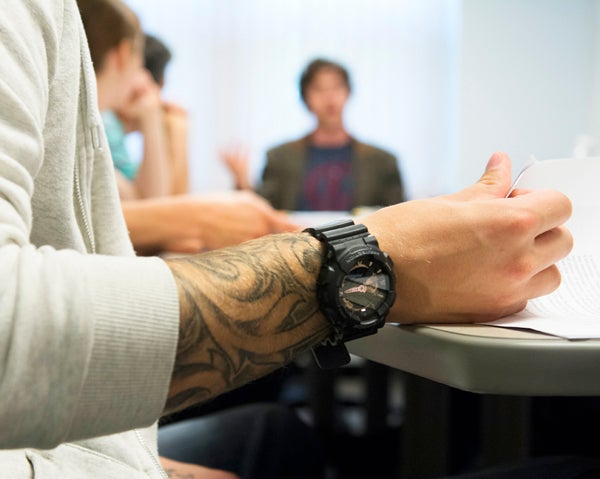 person’s arm with tattoo in a writing class