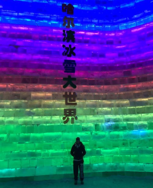 A student standing in front of a multicolored colored ice structure with Chinese characters
