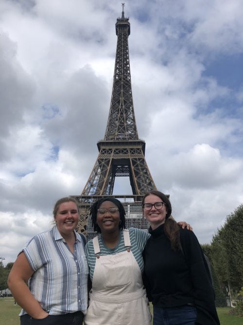 Three students stand in front of the Eiffel Tower