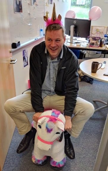 Thomas Wenisch riding an electric unicorn in his office at the University of Michigan.