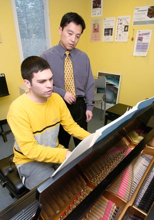 student playing piano with teacher watching