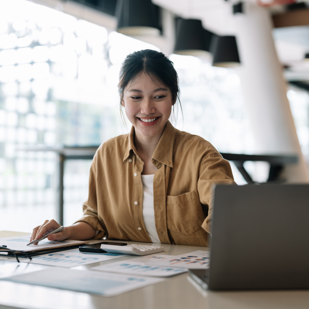 A young woman smiles while working on her computer