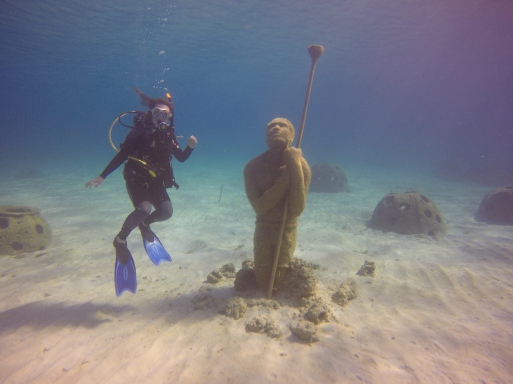 Casey diving at the Coral Reef Sculpture Garden. This statue is the "Virtuoso Man" who is passing the torch of marine conservation on to future generations.