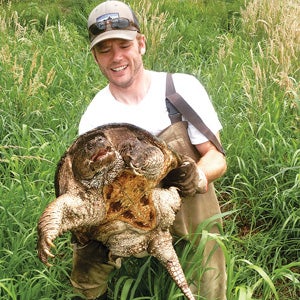 URI doctoral student Scott Buchanan handles a snapping turtle during his research.