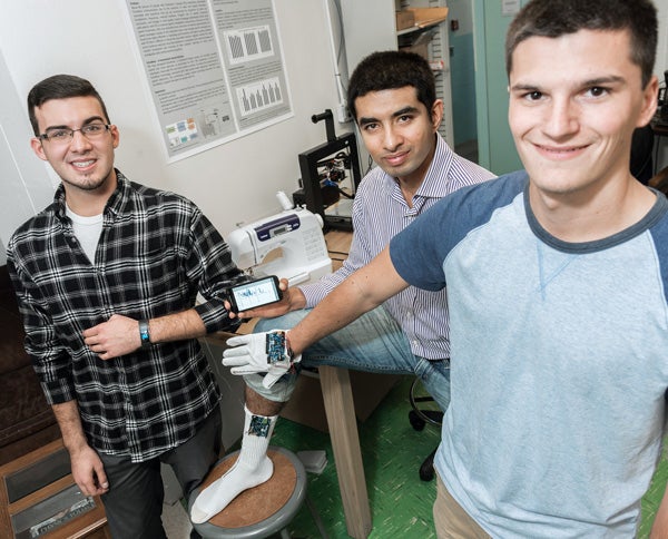 Professor Kunal Mankodiya (center), Nick Peltier ’17 and Matt Constant ’18 display smart textiles. Peltier and Constant are creating a smartwatch app that will help people with autism. 