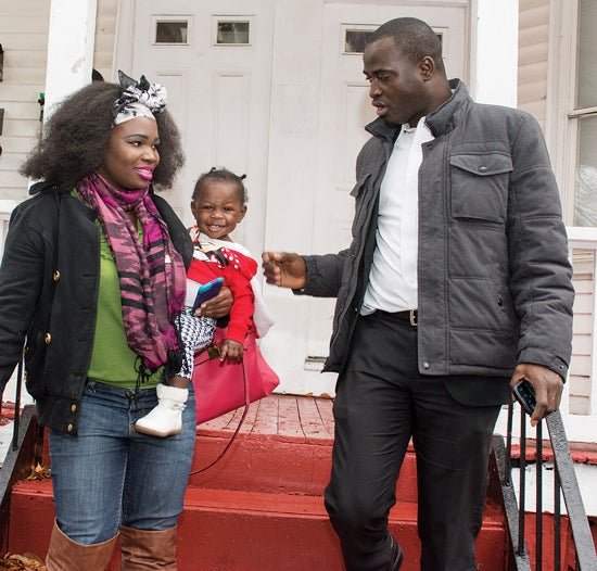 Revokata Nzinahora—carrying her daughter, Hervin Nadia Dominque—talks with Omar Bah at her apartment in South Providence.