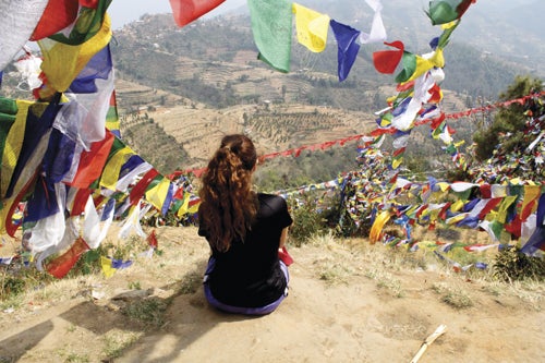 Natascha Shea ’14 contemplates the enduring view from a mountain in Bharatpur during the Center for Nonviolence and Peace Studies 2013 Alternative Spring Break in Nepal. Prayer flags surround her, offering their blessings to the wind.
