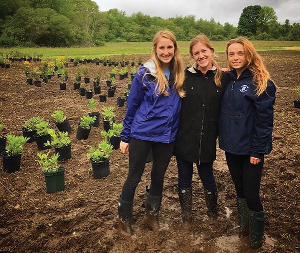 URI CELS students Becky Gumbrewicz, Sara Tucker and Sara Dotson pose as they prepare to plant a pollinator garden at URI
