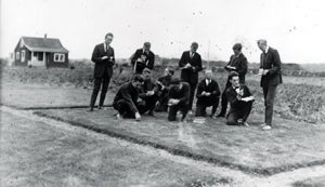 Vintage photo of students looking at a patch of grass.