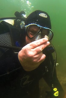 David Robinson examines one of several pieces  of quartz chipping debris from ancient Native American stone  tool manufacture found at the underwater site