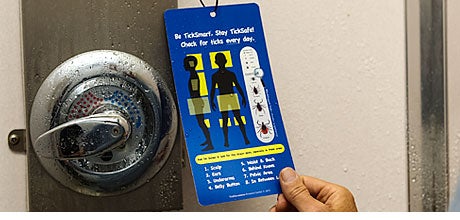 The TickSmart shower card hanging by a shower handle