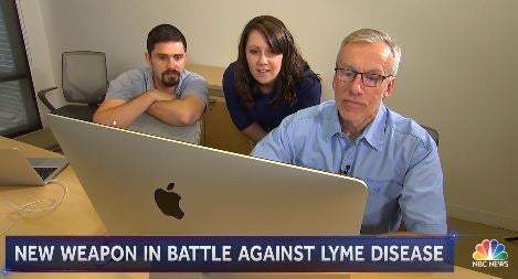 Dr. Thomas Mather looking at computer with students on the news