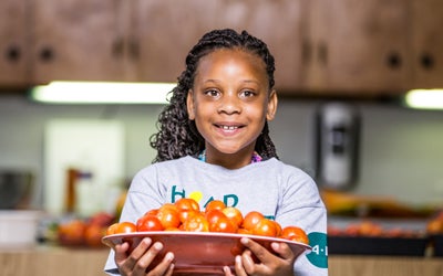 a girls holds a plate of tomatoes