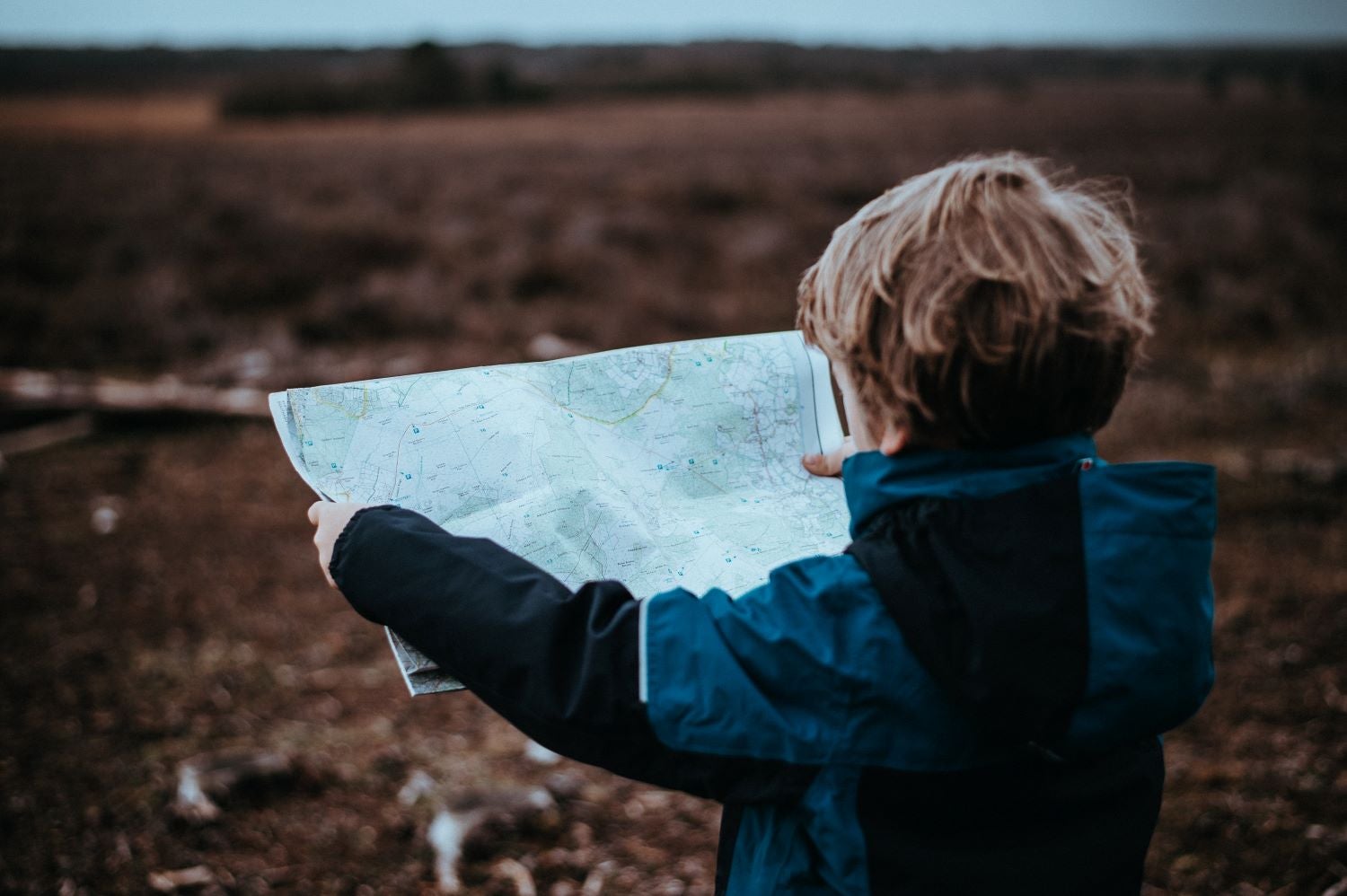 child facing away holding a map outside