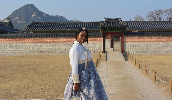 A student poses in a traditional Japanese costume in front of a historic monument
