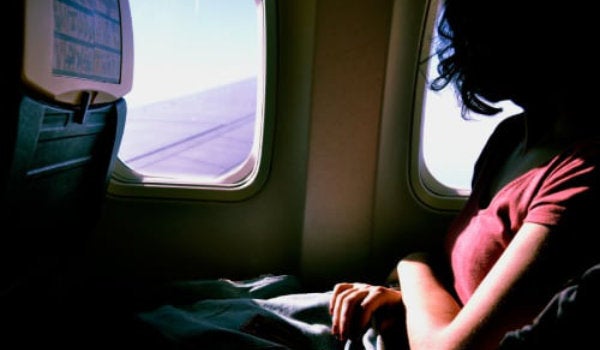 A student on an airplane, looking out the window.