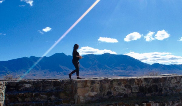 A student walking on a wall before the mountains in Oaxaca