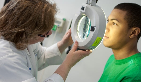 A student at a doctors appointment getting an examination by a magnifying instrument