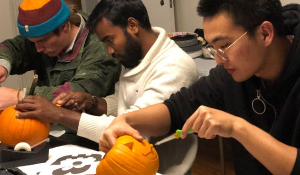 A group of international students carving traditional Halloween pumpkins