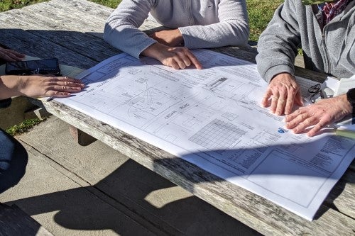 Hands pointing at a plan of a septic system