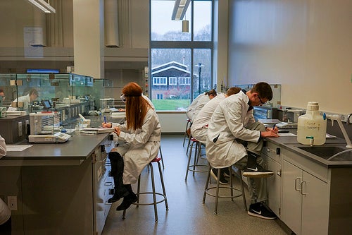 Two students in lab coats working on a project.