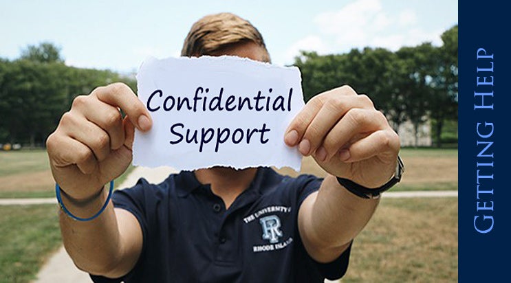 URI Student holding up confidential support sign