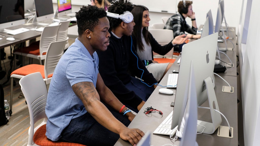 Students sitting in front of a computer monitor engaged in working on a computer