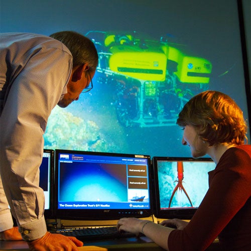 Professor Steven Carey and a student check a feed from E/V Nautilus in GSO's Inner Space Center.