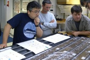 Scientists looking at sediment cores aboard a research vessel.