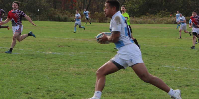Member of the rugby team running with the ball