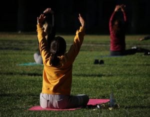 student participating in a Yoga on the Quad group exercise class. sitting on the grass