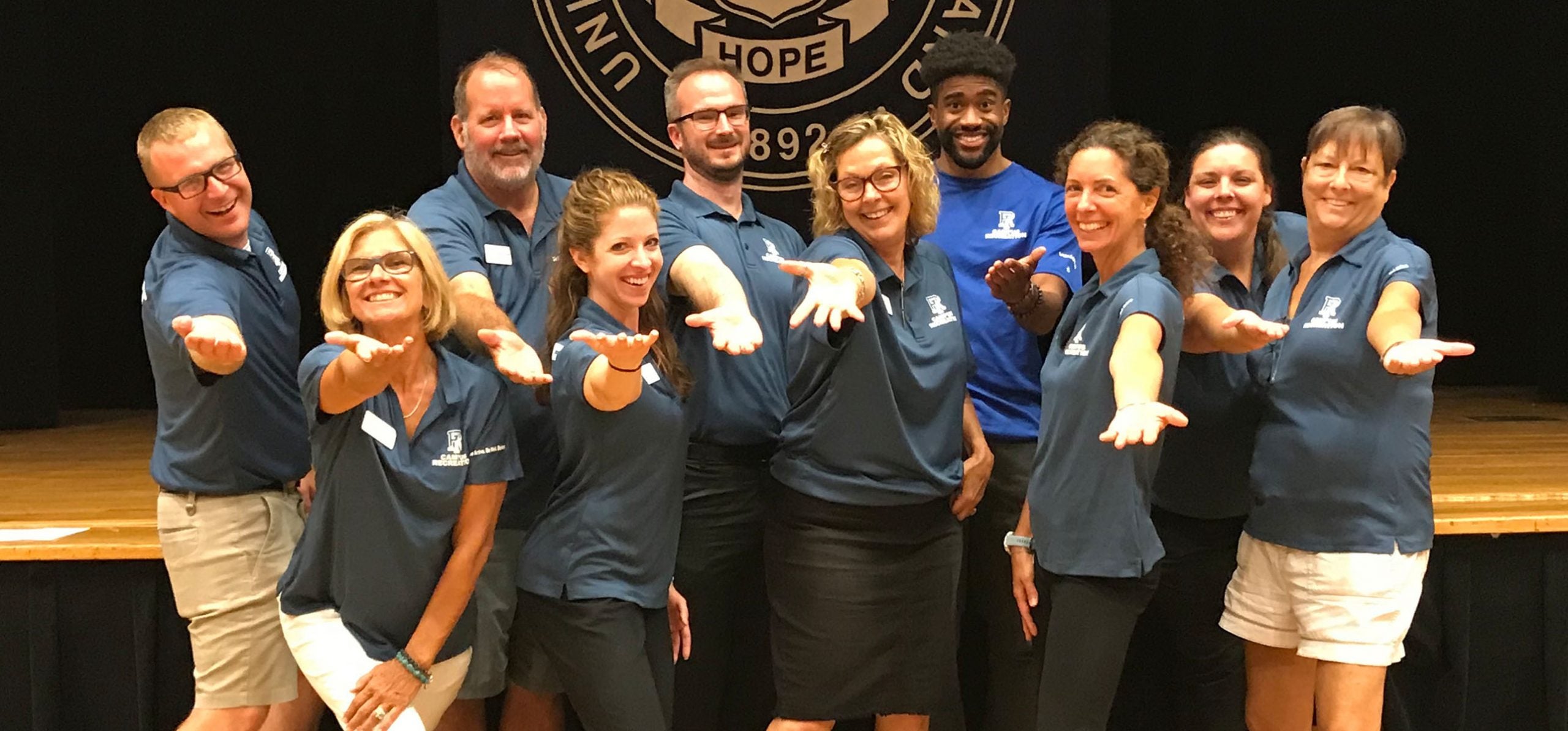 uri campus rec professional staff standing together with outstretched hands