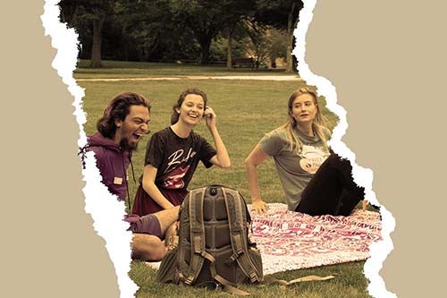 students laughing while sitting on a blanket on the URI quad